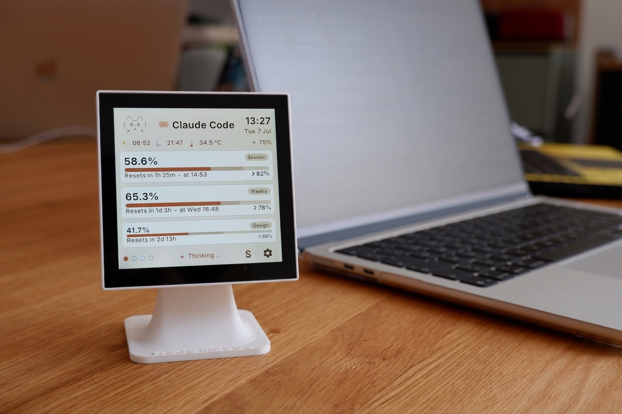 TokenMonitor 4-inch desk display on a wooden desk beside a laptop, showing live Claude Code usage